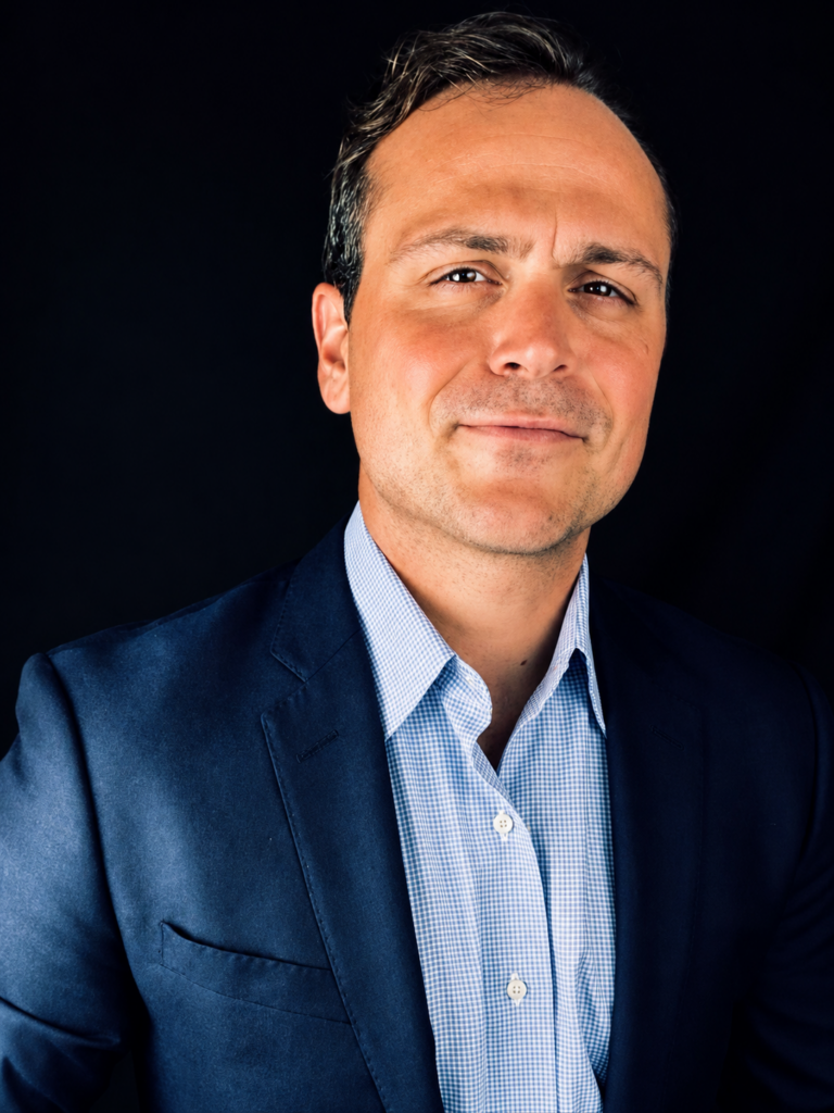 Headshot of a Georgetown University professor wearing a suit jacket and dress shirt in front of a dark background.