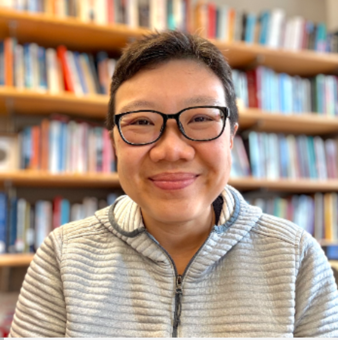 A professor with short hair wearing glasses and smiling.