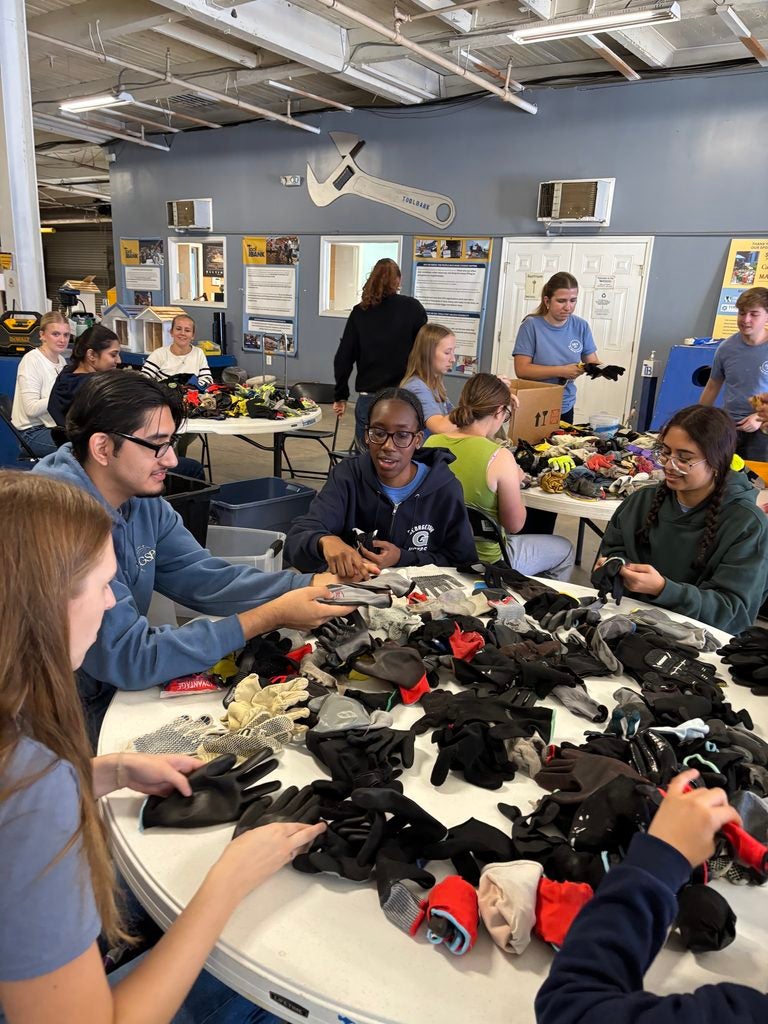 A group of Georgetown students sitting around a table and sorting gloves.