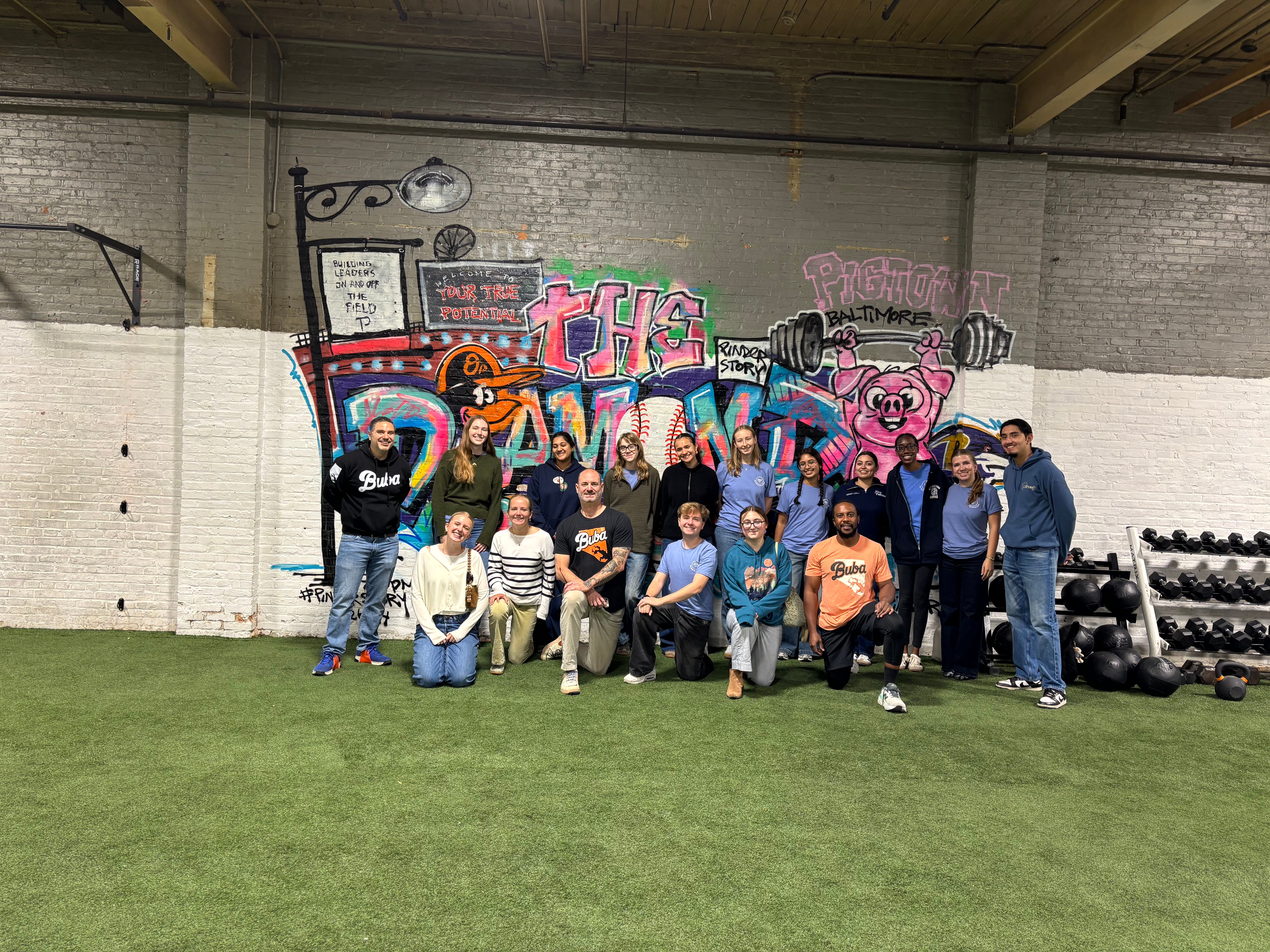 A group of Georgetown University students standing in front of a white brick wall with nonprofit members. 