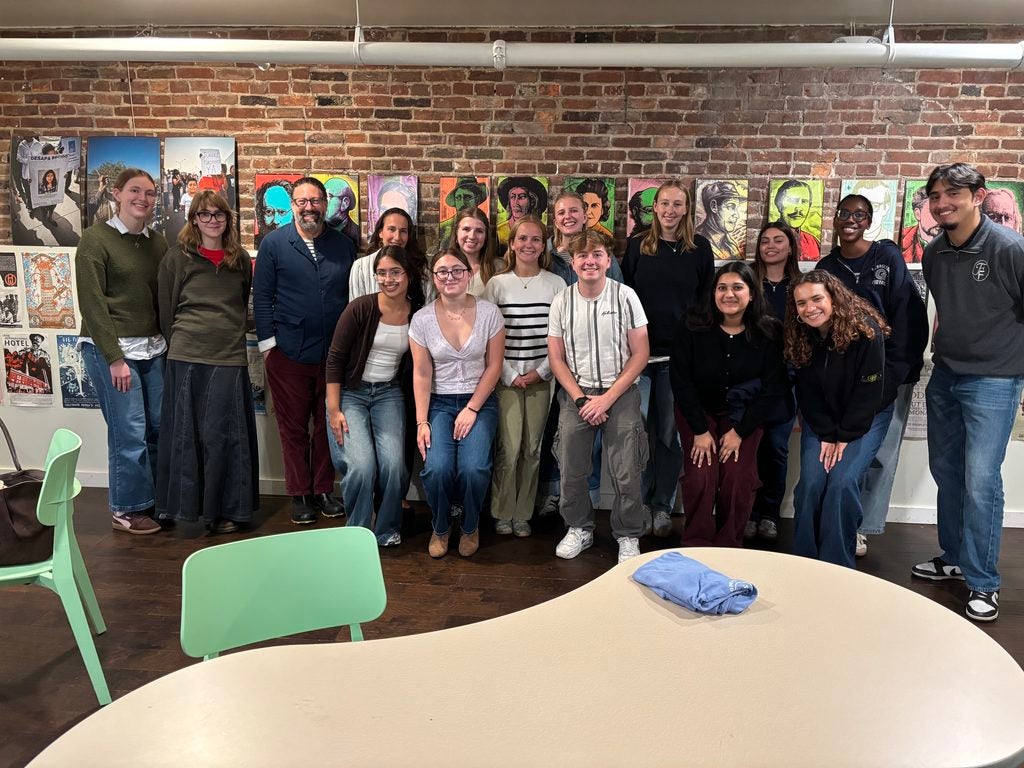 A group of Georgetown University students and alumni smiling in front of a brick background.